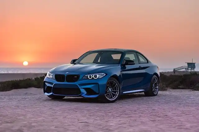 Beispielbild eines Autos. Abgebildet wird ein BMW in blau bei einem Sonnenuntergang.